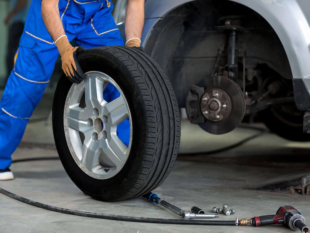 Mechanic changing car tire in workshop.